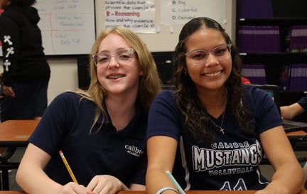 Two middle school female students smiling at their desk