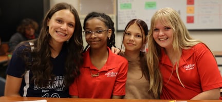 calibre students sitting together at a desk and smiling