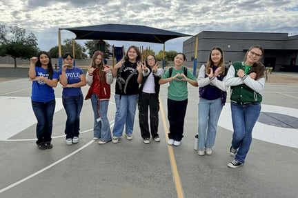 pre teen students standing outside in the basketball court smiling