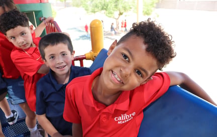 three calibre students smiling on play structure