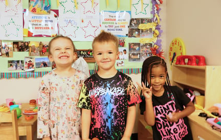 three pre-k students smiling in the classroom (1)