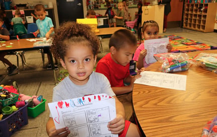 three students showing their work at their table
