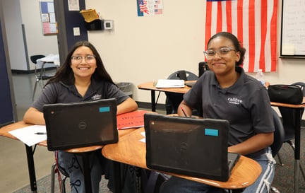 two calibre students smiling at their desk